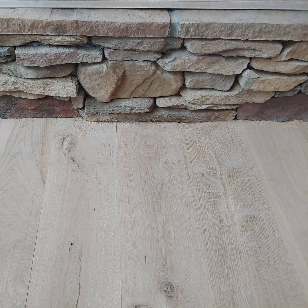Stone wall above light-colored wood flooring, showing a natural texture contrast.