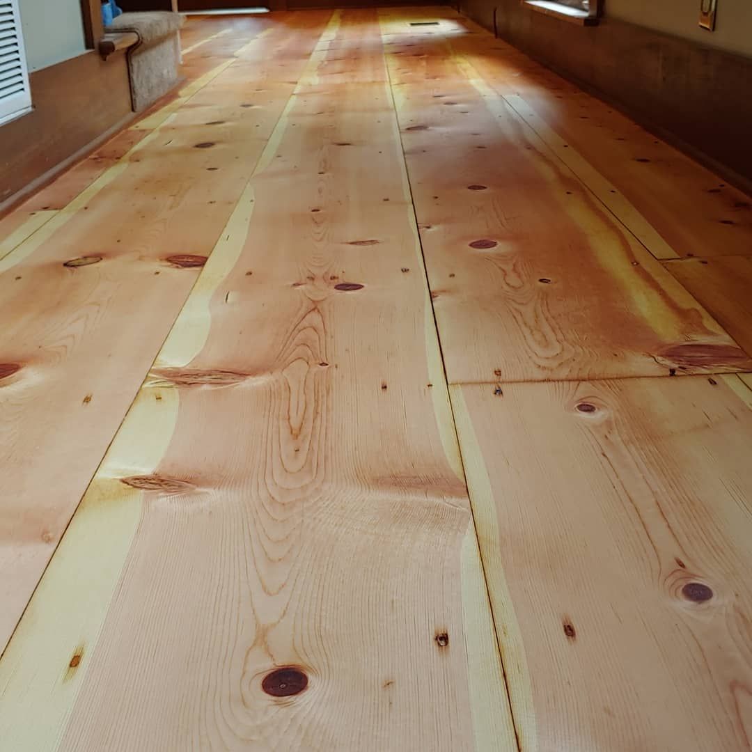 Wooden floor planks, light brown with darker knots, extending into the distance.