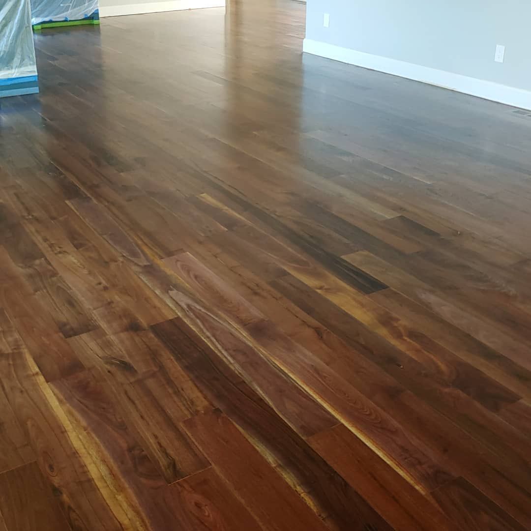 Shiny, dark wood floor with varied grain and color, in a brightly lit room.