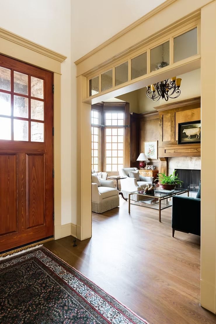 Wooden door and interior entryway with hardwood floors leading to a living room with a fireplace.