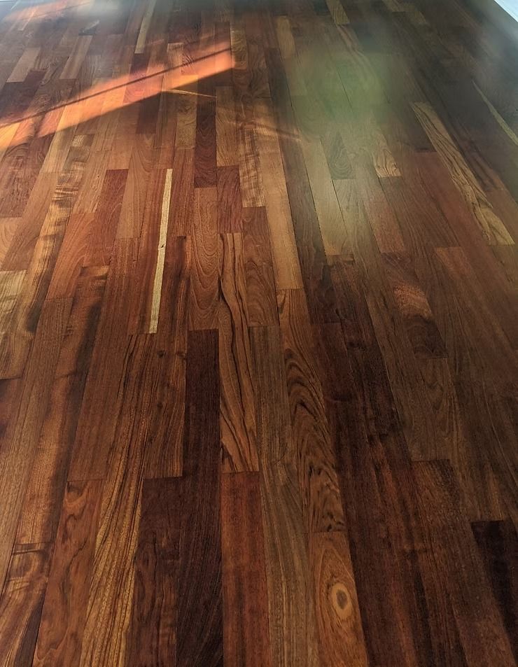 Wooden floor with varied wood tones, possibly reflecting light.