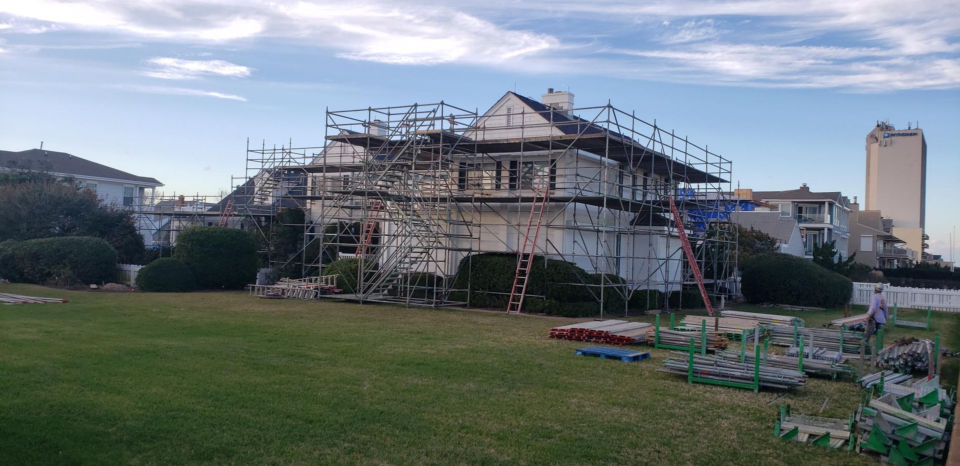 House under construction with scaffolding in a grassy field at dusk