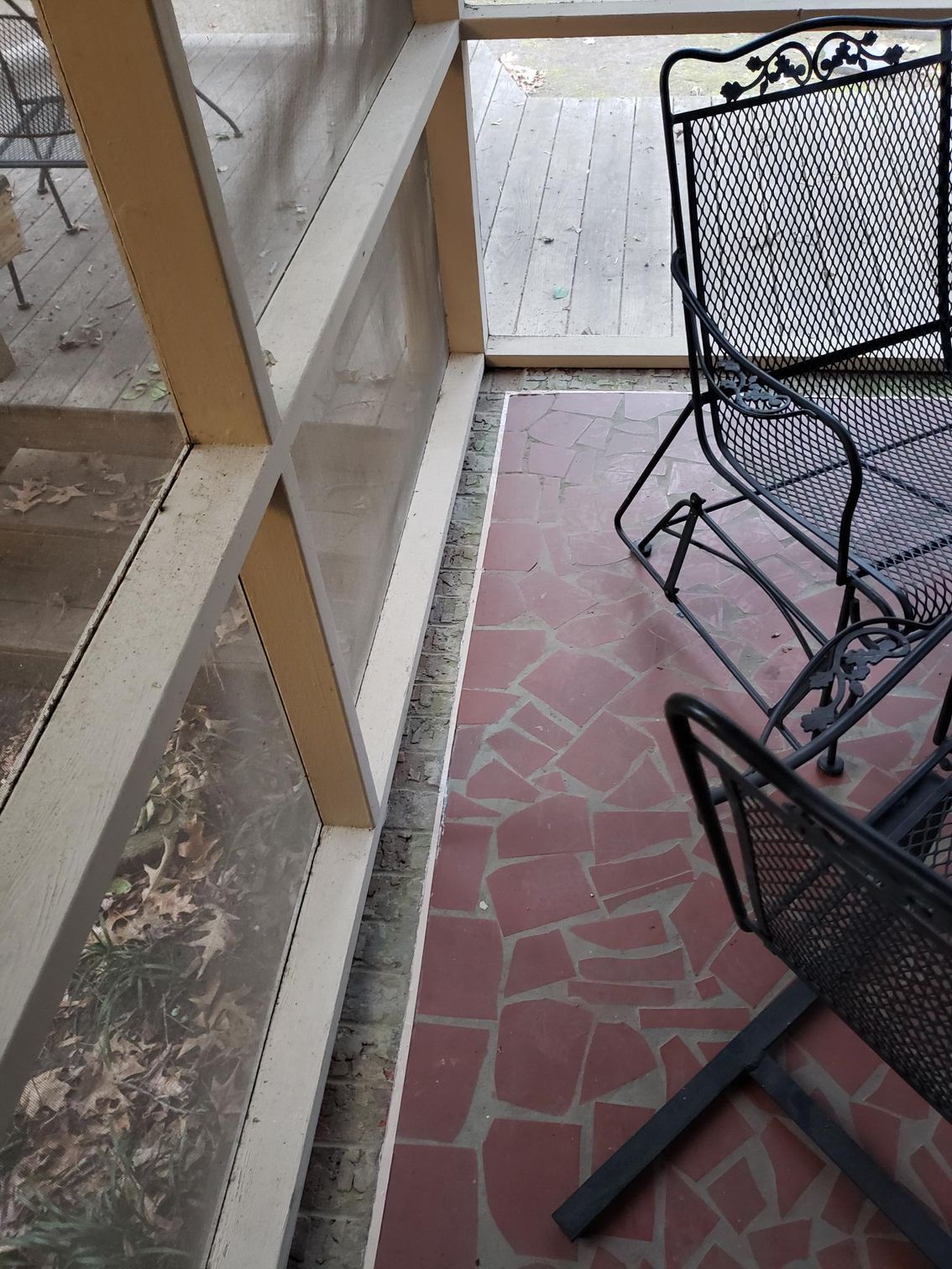 Outdoor patio with black metal chairs beside a white railing and brick-tiled floor