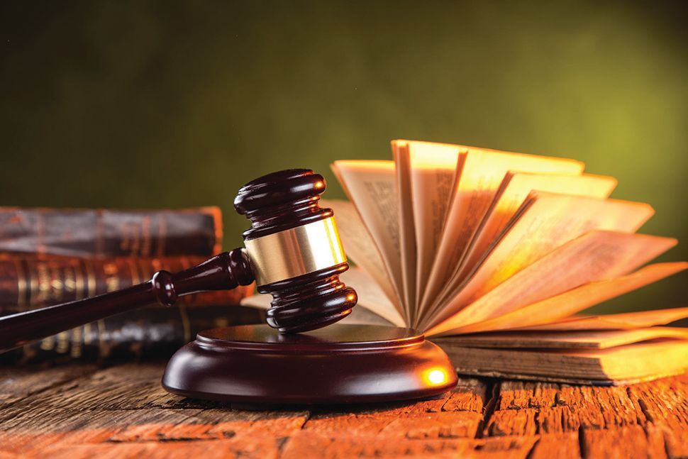 A judge's gavel sits on a wooden table beside an open book.