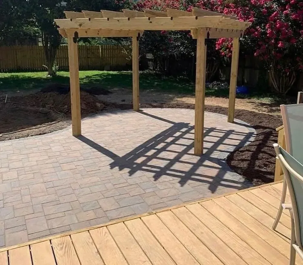 A wooden pergola is sitting on top of a wooden deck.