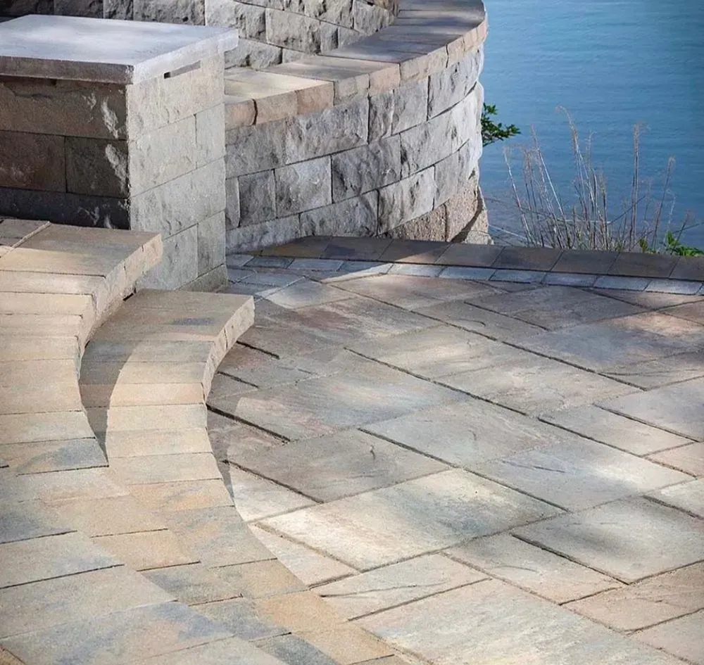 A patio with a stone wall and steps leading to the water