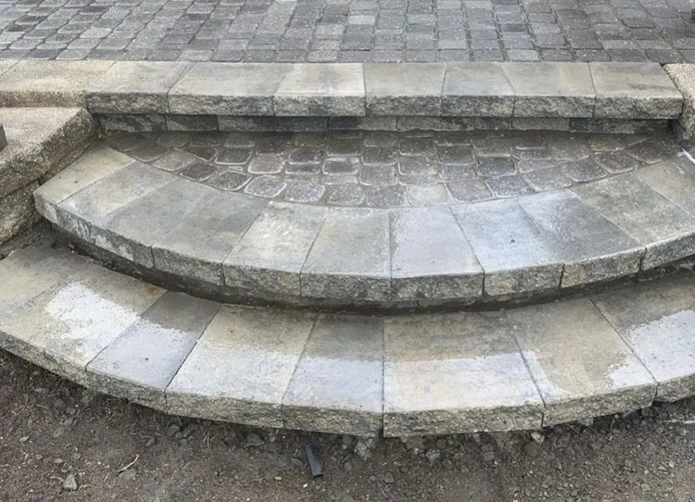 A set of stone steps leading up to a brick patio.