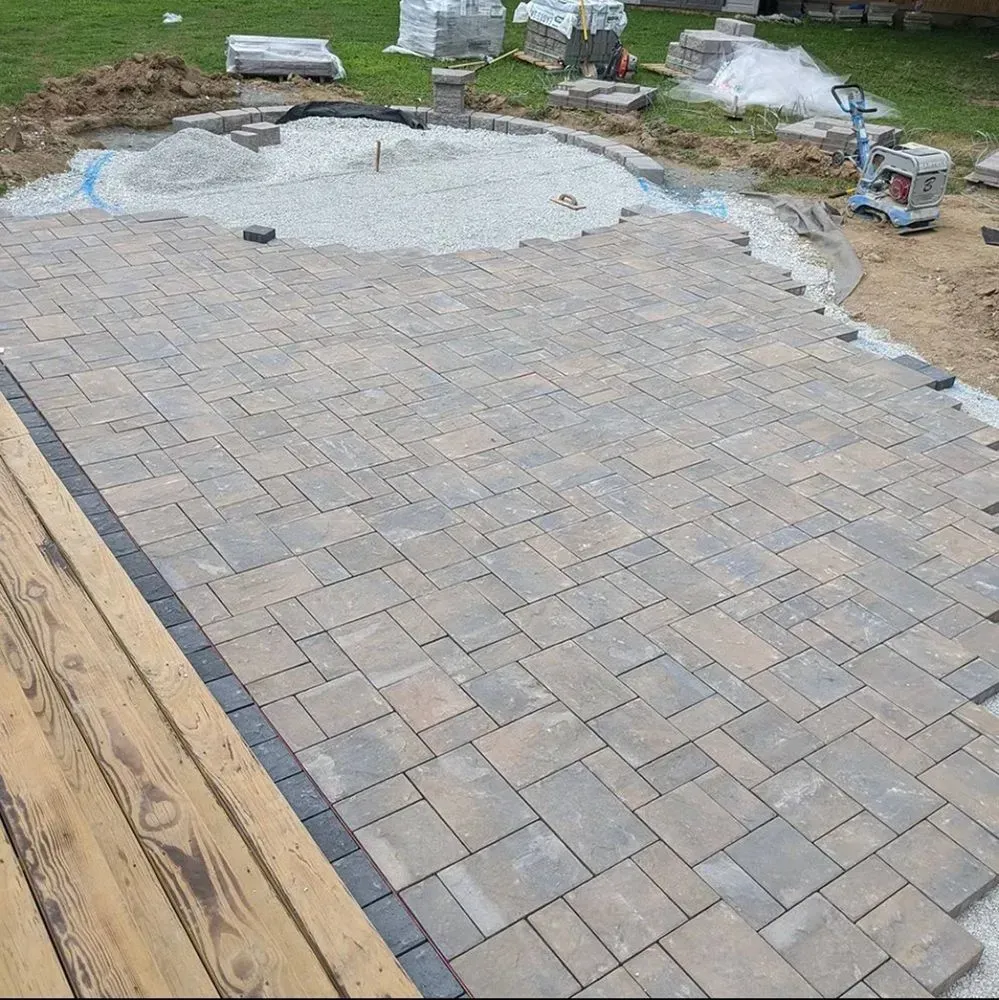 A brick patio is being built in a backyard.