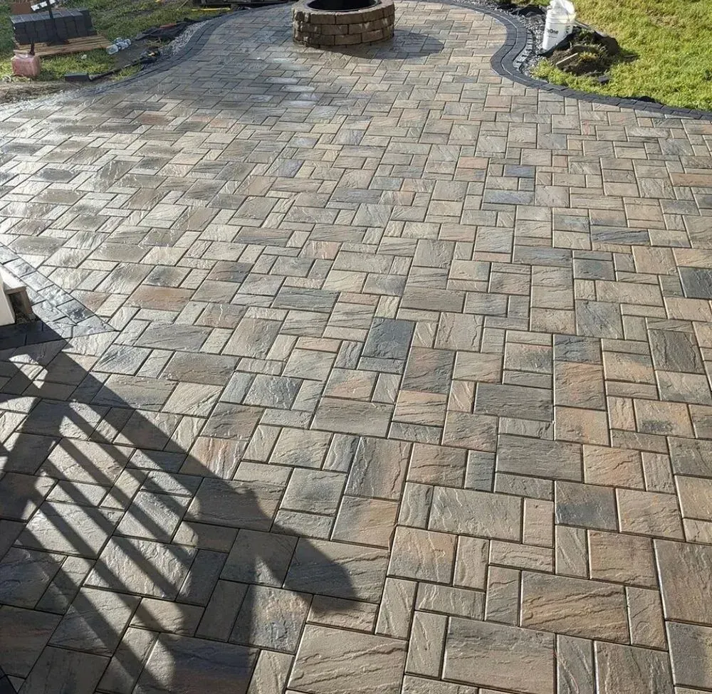A brick patio with a fire pit in the middle of it.