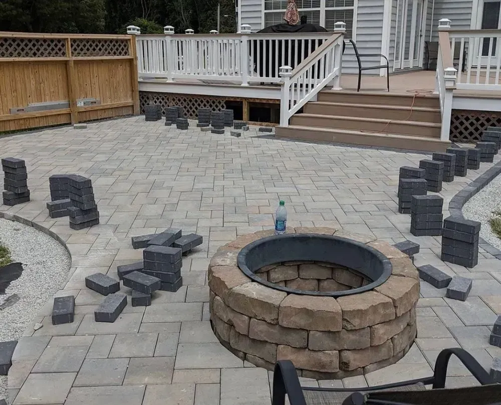 A fire pit is being built on a patio in front of a house.