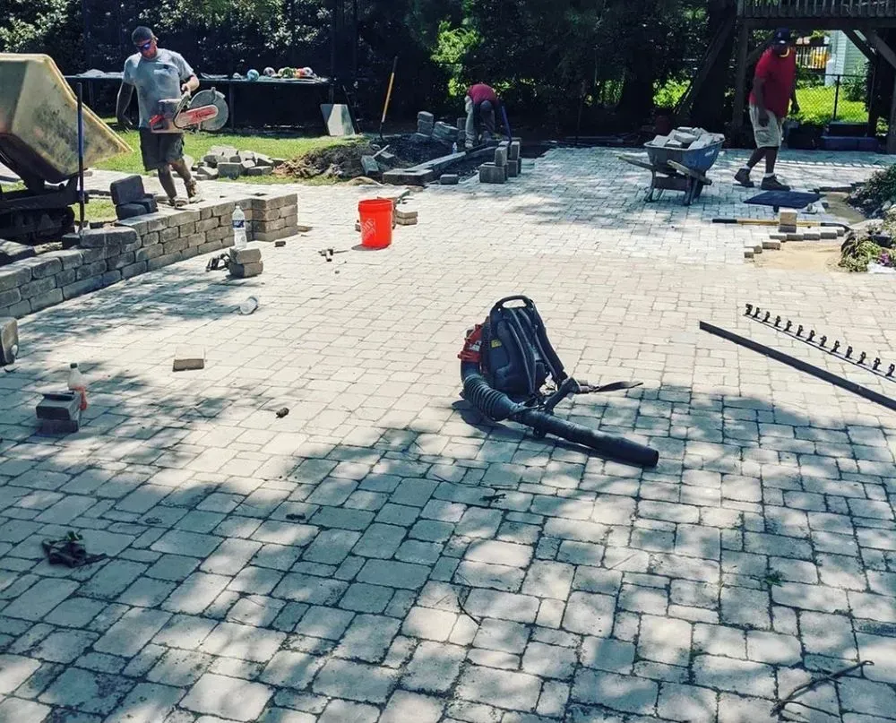 A backpack is laying on the ground on a brick patio
