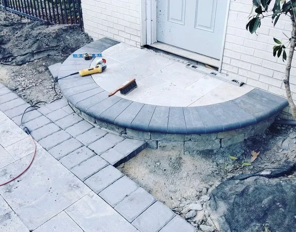 A brick walkway is being built in front of a house.