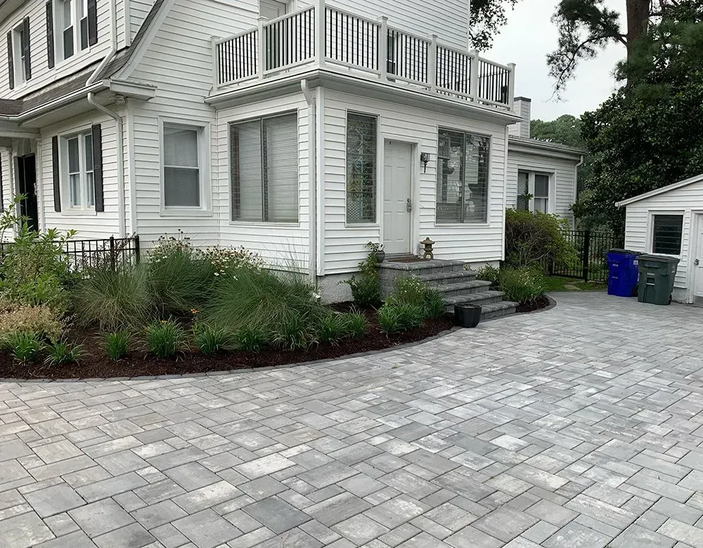A large white house with a brick driveway in front of it.