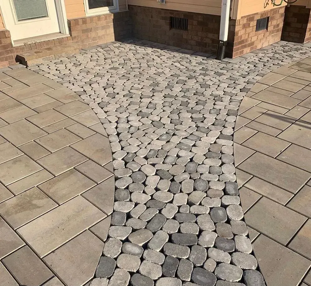 A walkway made of bricks and rocks in front of a house