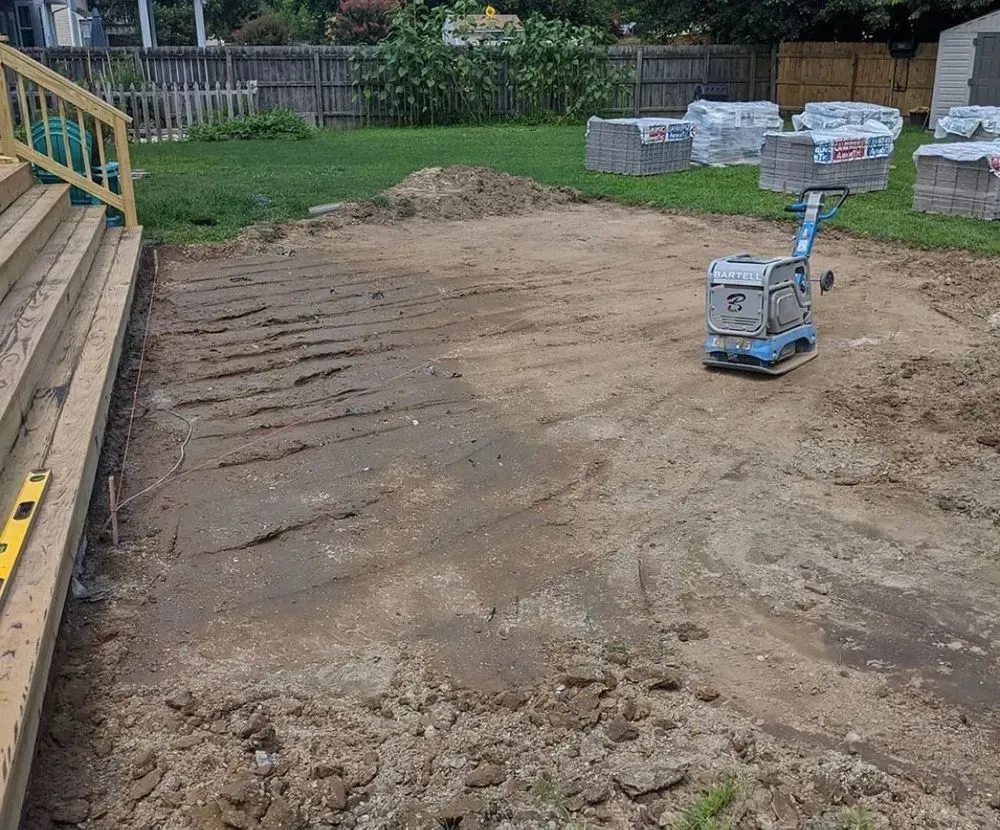 A machine is sitting on top of a pile of dirt in a yard.