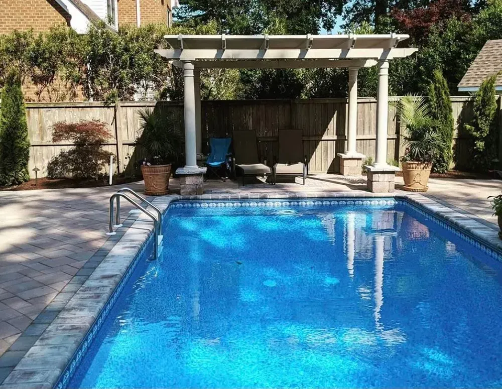 A large swimming pool with a pergola in the backyard