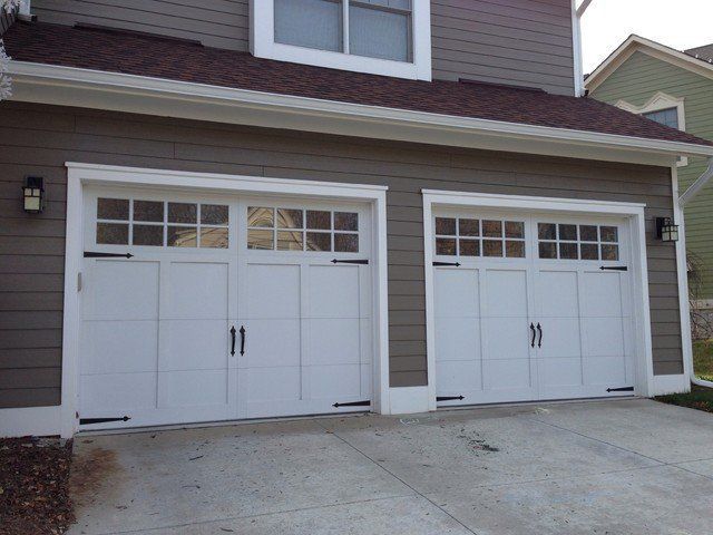 Two white garage doors are on the side of a house
