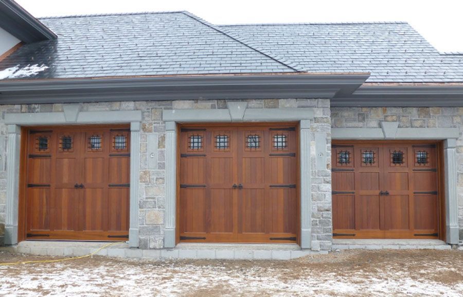 A house with three wooden garage doors and a slate roof