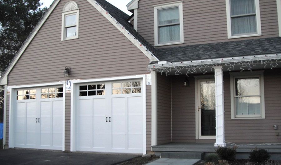 A house with two white garage doors and a porch