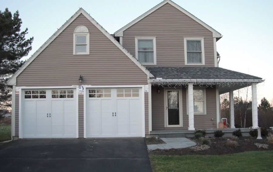 A house with two white garage doors and a porch
