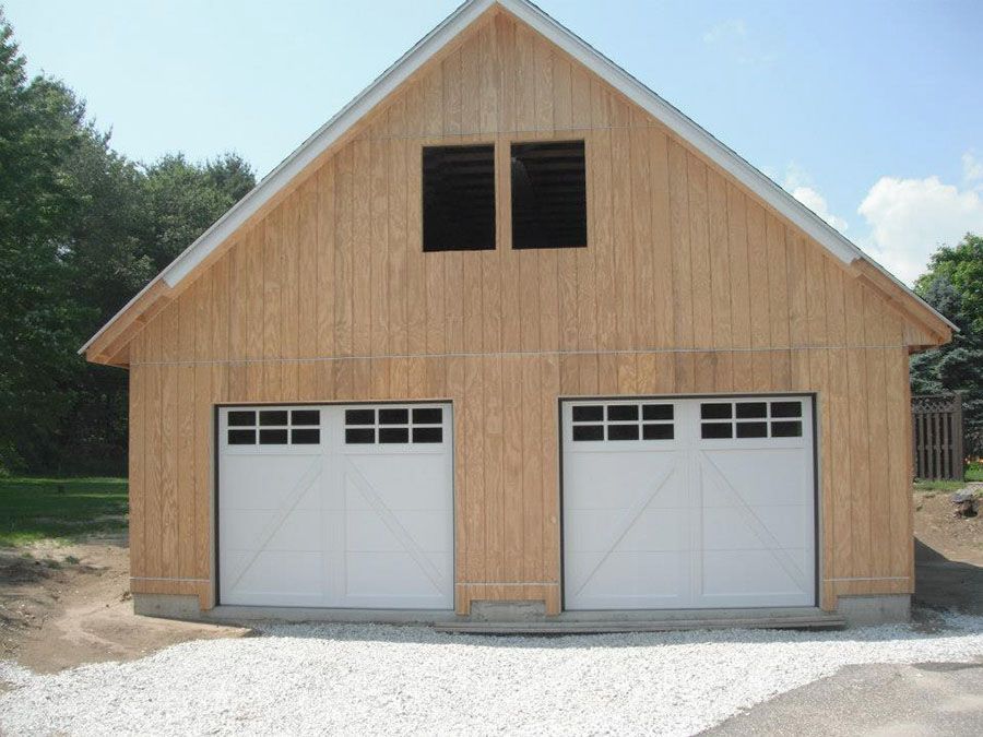 A wooden garage with two white garage doors