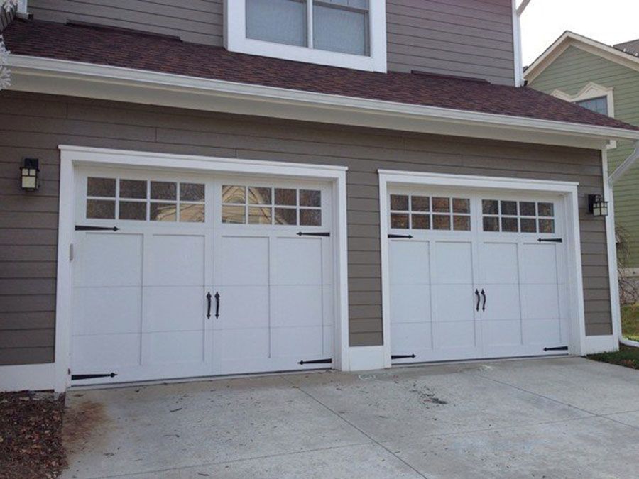 Two white garage doors are on the side of a house
