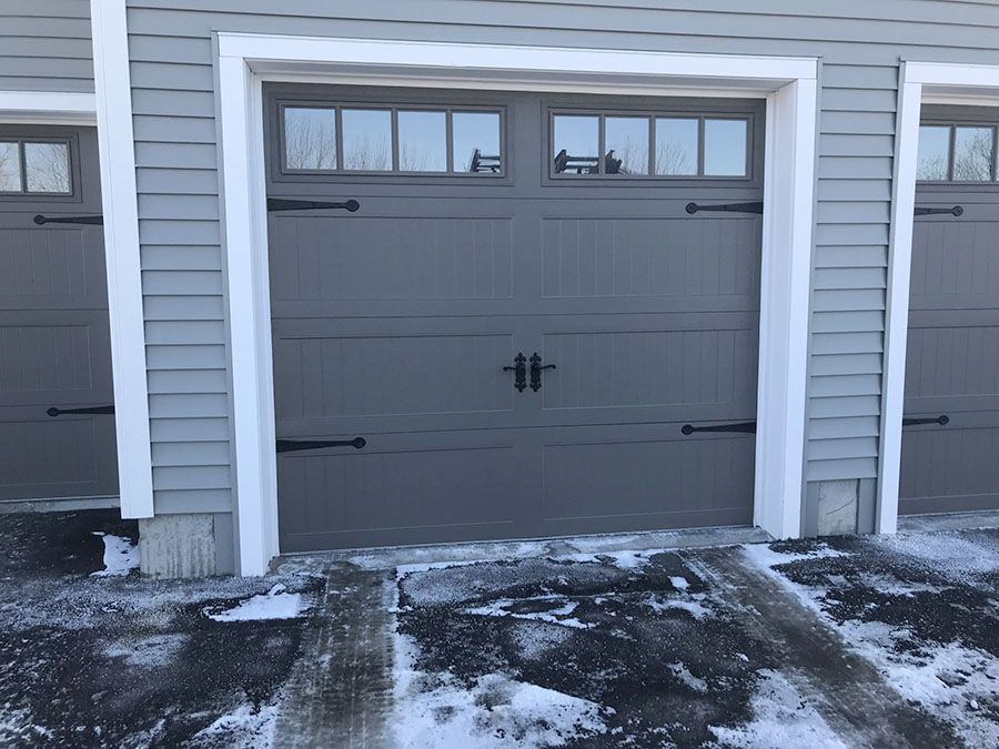 A row of garage doors on a house with snow on the ground