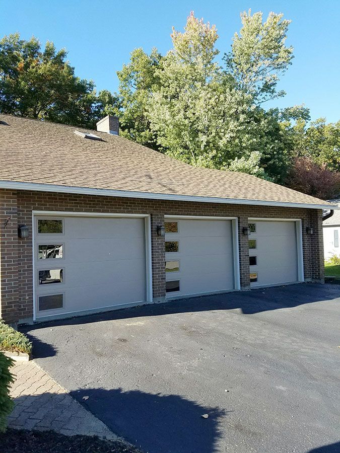 A brick house with three garage doors and a driveway