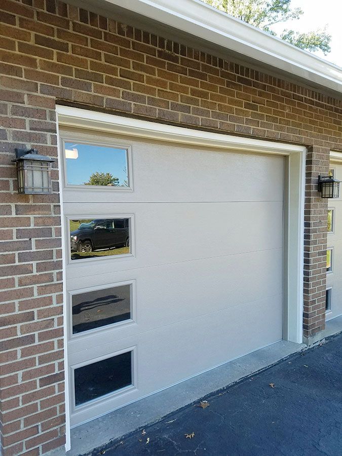 A white garage door is on a brick building