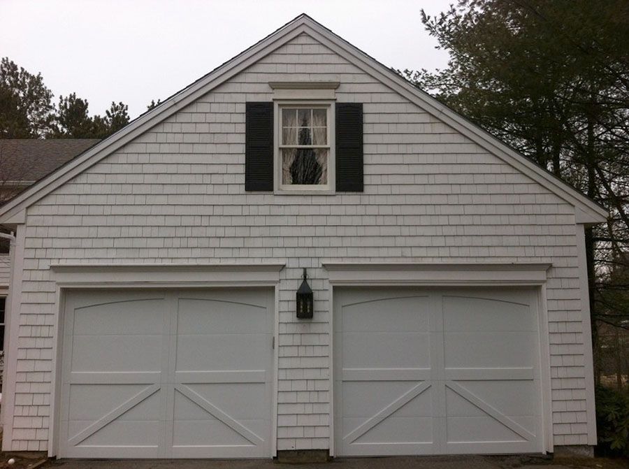 A white garage with black shutters and a window