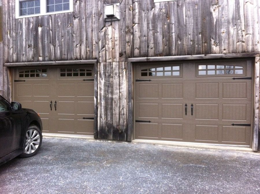 A car is parked in front of two garage doors