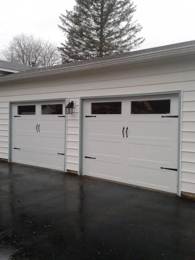 A white garage door with a black asphalt driveway