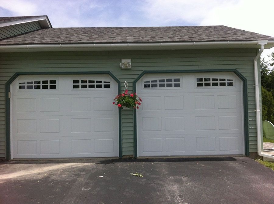 A garage with two white doors and a hanging basket of flowers