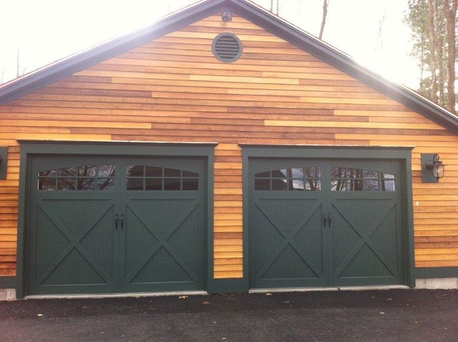 A garage with green doors and a wooden siding