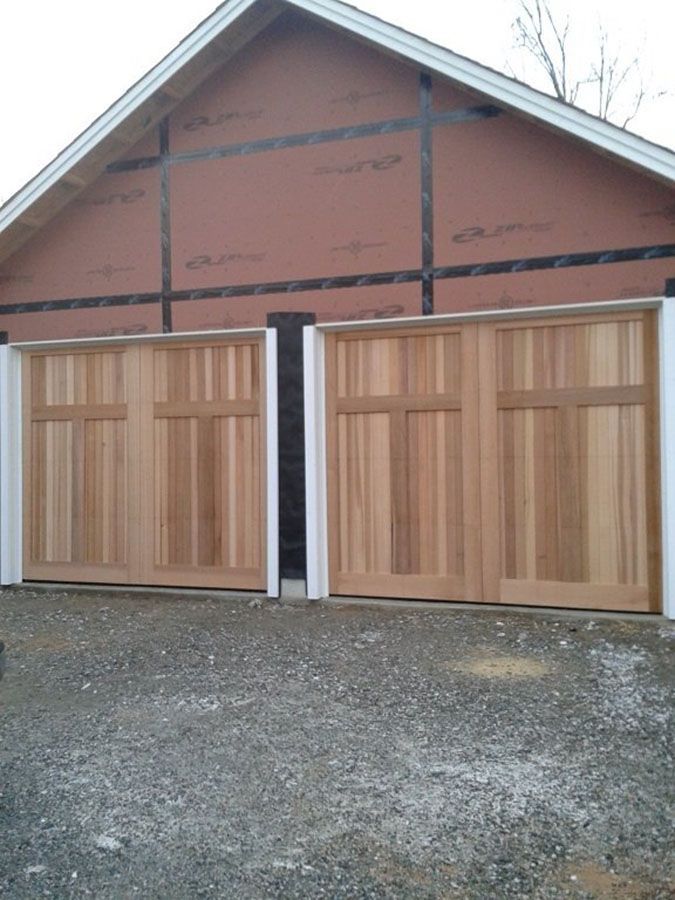 Two wooden garage doors on a house under construction