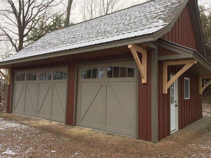 A red garage with gray garage doors and a snowy roof