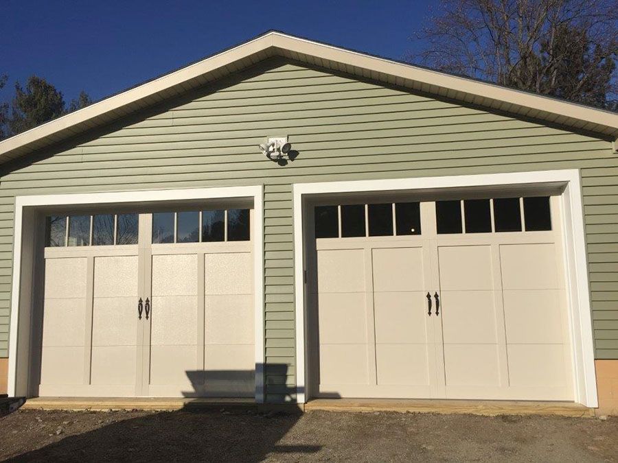 A garage with a green siding and white garage doors