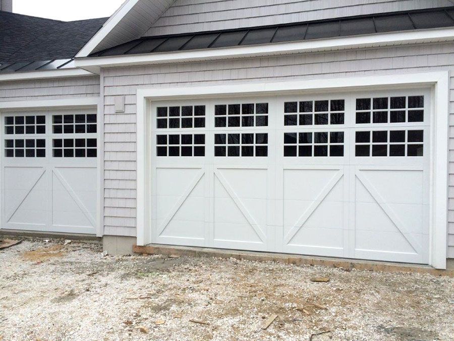 A house with two white garage doors and a black roof