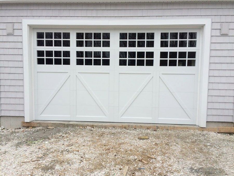 A white garage door is sitting on top of a gravel driveway