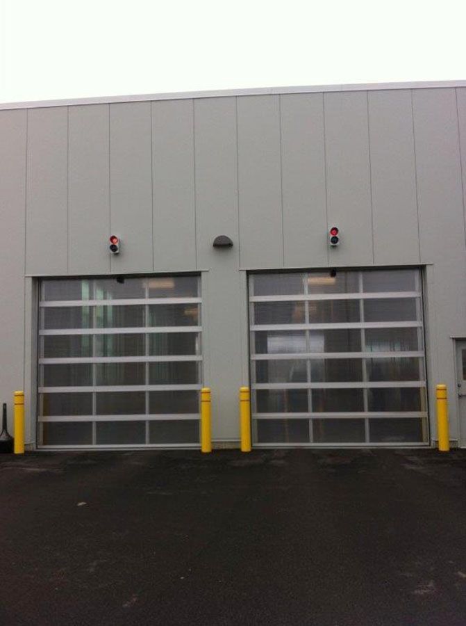 A building with two garage doors and yellow poles in front of it