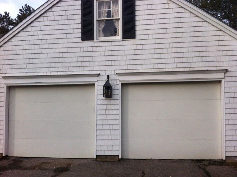 A white house with two garage doors and a window