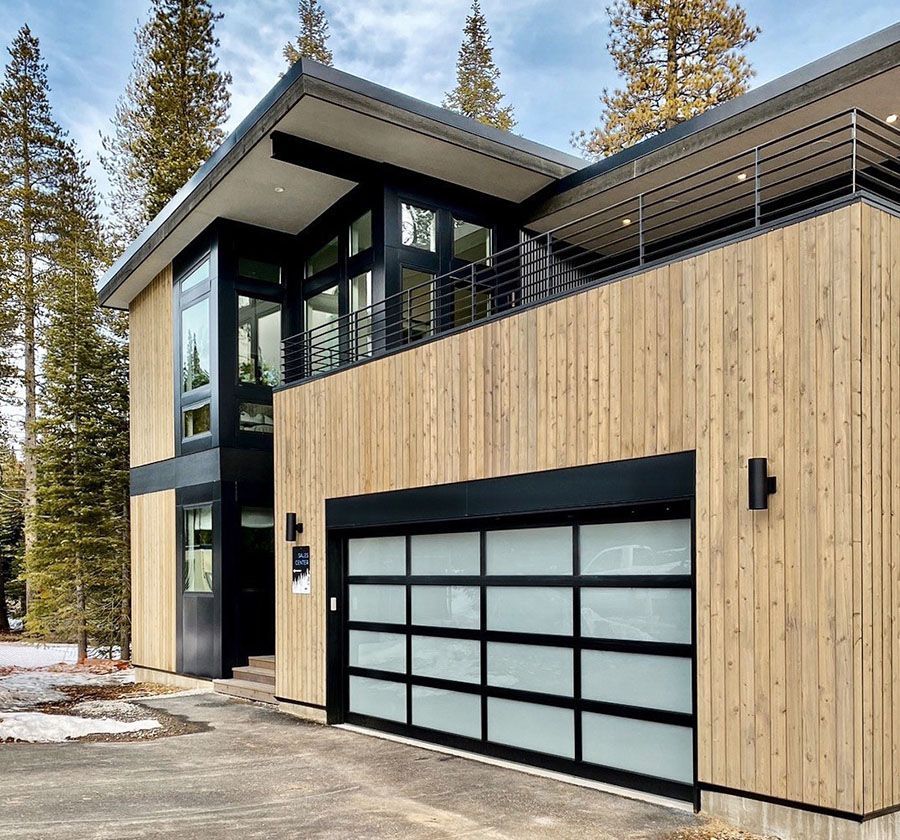 A modern wooden house with a black garage door