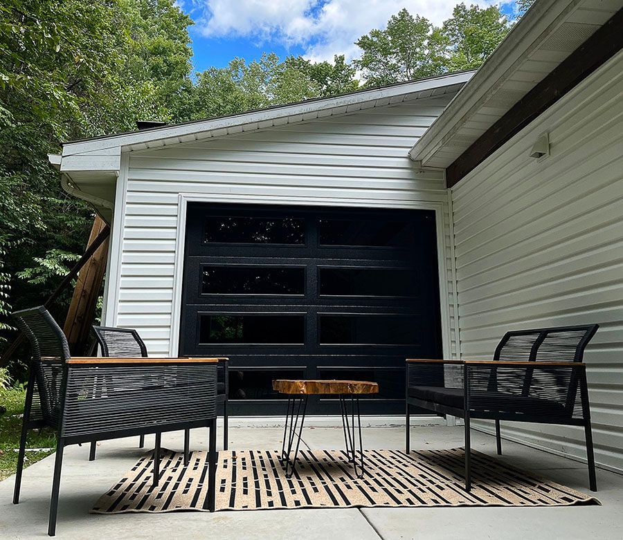 A patio with chairs and a table in front of a garage door