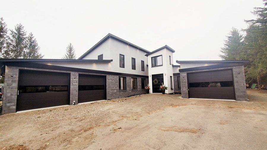 A large house with three garage doors and a driveway in front of it