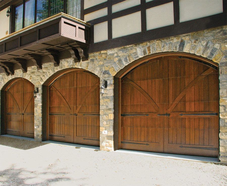 Three arched wooden garage doors on a stone building