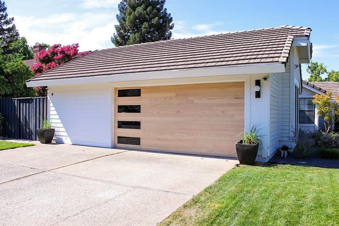 A white house with a wooden garage door and a driveway