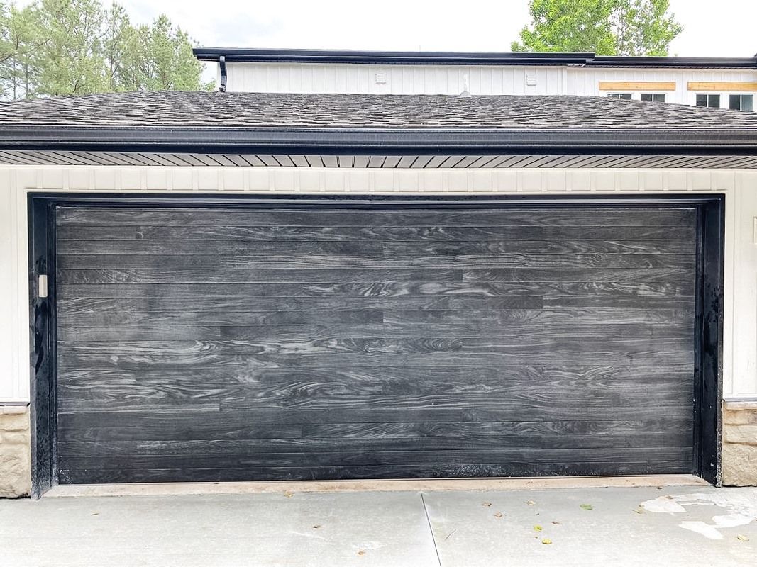 A whit house with a huge black garage door