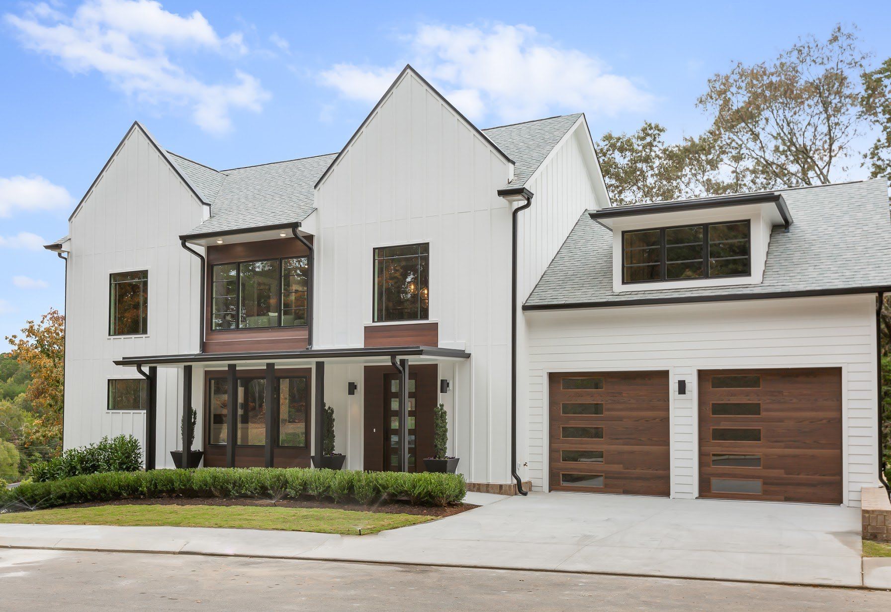 A large white house with wooden garage doors and a porch