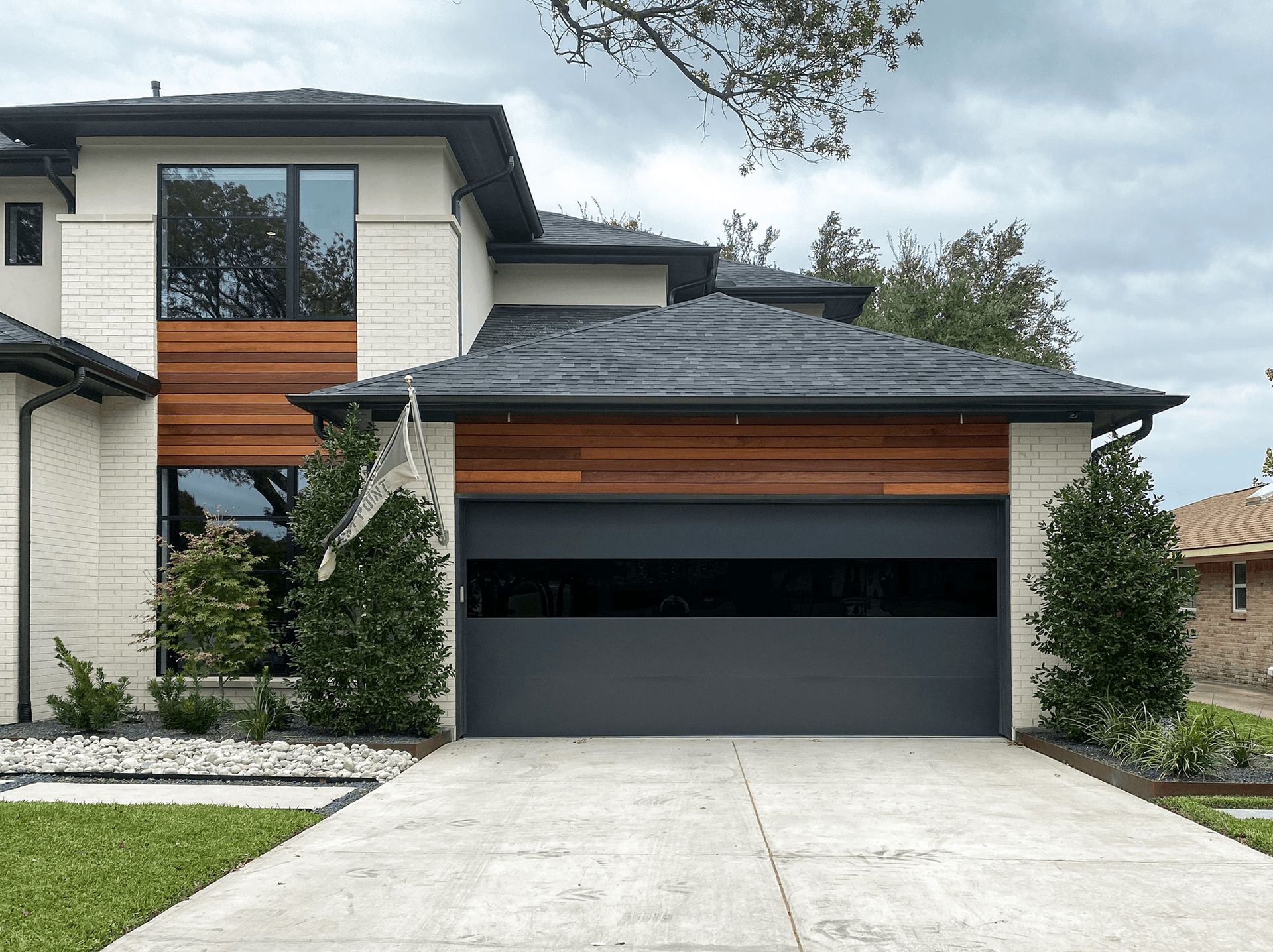 A modern house with a black garage door and a driveway
