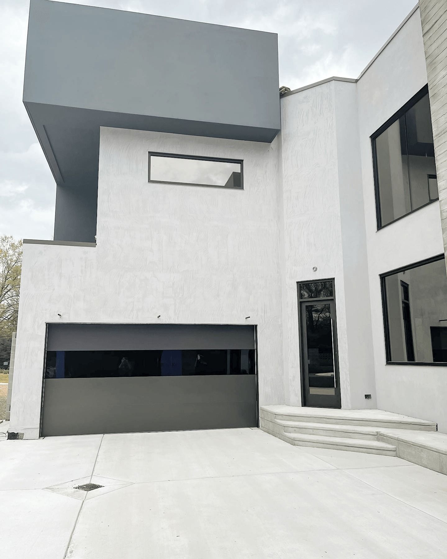 A large white house with a black garage door and stairs